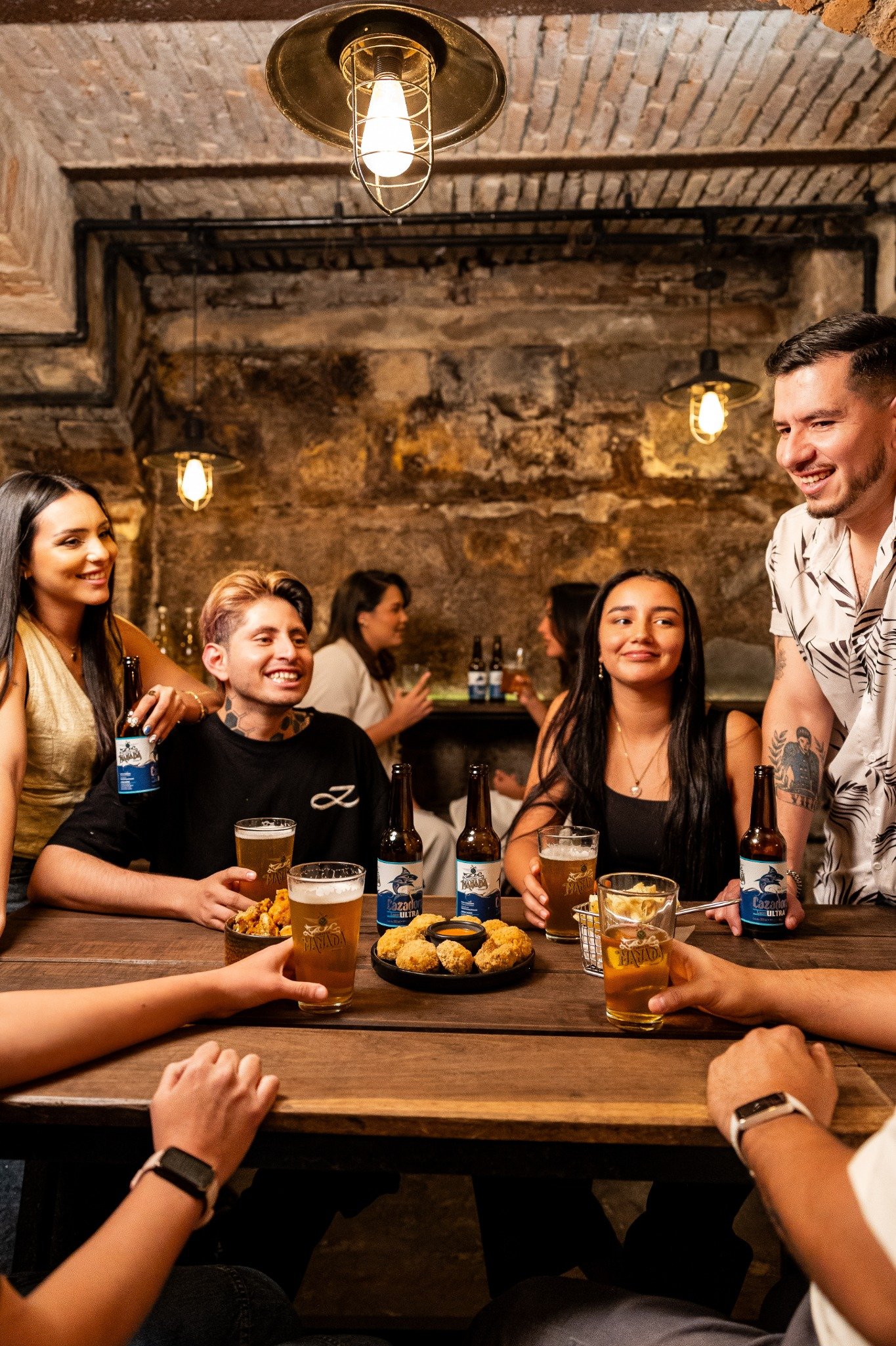 Amigos compartiendo cerveza Manada alrededor de una mesa